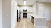 Located at 25335 Alessandro Blvd in Moreno Valley, CA, this 800-square-foot single-story unit offers 2 bedrooms and 2 bathrooms with a clean, modern aesthetic throughout. Light wood-look flooring and neutral gray-toned walls create a bright, cohesive feel across all rooms.

The open living area is spacious and airy, featuring a ceiling fan with light fixture, recessed lighting, and an arched entryway leading toward the hallway. The kitchen is well-appointed with white shaker-style cabinetry, light quartz countertops, a stainless steel refrigerator, gas range, microwave, and dishwasher, complemented by a skylight-style overhead fixture that brightens the space.

The primary bedroom measures 160 square feet and includes a ceiling fan and a sliding-door closet. The second bedroom is similarly finished with a ceiling fan and ample natural light from a window with exterior views. A dedicated walk-in style closet with wire shelving systems provides generous storage.

Both bathrooms are identically finished with white tub/shower combos featuring tiled surrounds, built-in shelving niches, white vanities with light countertops, and wood-look flooring. A connecting hallway ties all rooms together efficiently, completing this well-designed, move-in-ready unit.