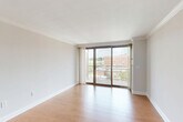 Located in Washington, DC's desirable West End neighborhood, this one-bedroom, one-bathroom residence at 2150 P St NW offers a well-designed layout across a single floor. The welcoming entrance flows into a bright, open living room finished with warm hardwood-style flooring and elegant crown molding throughout. A wall of floor-to-ceiling sliding glass doors opens to a private balcony, flooding the space with natural light and offering views of the surrounding cityscape.

The kitchen is thoughtfully appointed with rich wood cabinetry, granite countertops, a textured tile backsplash, and a full suite of stainless steel appliances including a refrigerator, range, microwave, and dishwasher. A granite-topped pass-through counter connects the kitchen to the living area, enhancing the open feel.

The bedroom is carpeted for comfort, featuring crown molding, a large window with city views, and access to a dedicated closet. The bathroom includes a glass-enclosed walk-in shower with decorative mosaic tile accents and granite countertop finishes. Neutral tones and clean lines throughout give the residence a calm, move-in-ready ambiance well-suited to urban living.