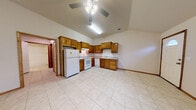 Located at 1906 N Second Ave in Canyon, TX, this single-floor home offers a practical and comfortable layout designed for easy living. The open-concept living and kitchen area is a standout feature, boasting vaulted ceilings that lend a sense of spaciousness and airiness to the space. Ceiling fans are installed throughout, providing both functionality and a finishing touch to each room.

The kitchen is well-equipped with warm-toned oak cabinetry offering ample storage, white appliances including a refrigerator, electric range, and dishwasher, and a double-basin sink set into light-colored countertops. The L-shaped layout maximizes efficiency, and light tile flooring extends seamlessly from the kitchen into the main living area.

The entry area welcomes guests with tile flooring, vaulted ceilings, and a large window that allows natural light to fill the space. The bedrooms feature plush carpeting and ceiling fans, with windows fitted with blinds for privacy and light control.

The bathroom is clean and functional, featuring a full tub and shower combination with built-in shelving and chrome fixtures set against neutral surroundings. Throughout the home, neutral wall tones and consistent finishes create a cohesive, move-in-ready atmosphere well-suited to a variety of lifestyles.