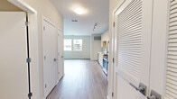 Located at 150 Glover Avenue in Norwalk, Connecticut, this efficiently designed studio offers a thoughtful open-plan layout that combines the kitchen and living area into a single, cohesive space. Light-toned luxury vinyl plank flooring runs throughout, lending a clean, contemporary feel that ties every room together seamlessly.

The kitchen is outfitted with sleek, flat-front cabinetry in an off-white finish that extends to the ceiling, maximizing storage. Stainless steel appliances include a gas range, over-the-range microwave, dishwasher, and refrigerator. White quartz countertops and an undermount sink complete the polished, functional workspace.

The living area benefits from a pair of windows that frame views of the surrounding neighborhood and invite generous natural light into the space. A sliding-door closet provides practical built-in storage. The neutral warm-beige wall tones and clean white trim create a bright, airy ambiance throughout.

The bathroom is finished with the same attention to detail, featuring a wide floating vanity with wood-toned cabinetry, a white quartz countertop, an undermount sink, a large wall-to-wall mirror, and a tub-shower combination. The consistent use of light materials and modern fixtures gives the entire unit a cohesive, move-in-ready aesthetic suited to contemporary urban living.