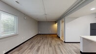 Located at 2084 S Hamilton Rd in Columbus, Ohio, this single-floor, one-bedroom, one-bathroom unit offers a practical and well-organized layout across a compact but functional footprint. The living room is the largest open area of the unit, featuring light-toned luxury vinyl plank flooring, neutral gray walls with dark baseboards, and exposed conduit along the ceiling that lends a utilitarian character to the space. Windows allow natural light to filter in, offering views of the surrounding greenery. The kitchen is efficiently designed with warm wood-toned cabinetry, light countertops, and a full suite of black appliances including a refrigerator, dishwasher, microwave, and cooktop, providing everything needed for everyday cooking. The bedroom offers a comfortable, dedicated sleeping area with its own closet for storage. The bathroom is designed with accessibility in mind, featuring grab bars, a roll-under vanity, tile flooring, and a walk-in shower equipped with a fold-down bench seat — making the space inclusive and practical. A dedicated utility room rounds out the unit's layout, providing additional functional space. Overall, the unit presents a clean, move-in-ready environment suited for straightforward, comfortable living.