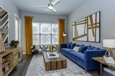 This thoughtfully designed single-floor residence offers a seamless blend of modern finishes and functional living spaces. The open-concept kitchen is a standout feature, showcasing rich dark-espresso cabinetry, granite countertops, a full suite of stainless steel appliances — including a refrigerator, range, microwave, and dishwasher — and a central island with bar seating, all set atop durable wood-style flooring. Pendant lighting adds a warm ambiance to the kitchen and dining area, which flows naturally into the adjacent entryway and living spaces. The living room is bright and welcoming, with large windows dressed in blinds and gold-toned curtains that invite generous natural light and outdoor views. The bedroom is a comfortable retreat featuring plush carpeting, a sizable window with views to the exterior, and direct access to a private bathroom. The bathroom is well-appointed with dark cabinetry, granite vanity countertops, a large mirror, wood-style flooring, and a walk-in shower. Throughout the space, a cohesive neutral color palette with gray walls and crisp white trim creates a calm and contemporary atmosphere, while closet and storage doors are neatly integrated into the layout.