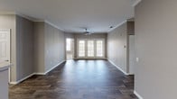 This single-story residence offers a well-organized, open layout designed for comfortable everyday living. The main living area is spacious and airy, finished with durable wood-look plank flooring and neutral warm-gray walls. Crown molding adds a refined touch, while a ceiling fan and French doors that open to the exterior fill the space with natural light and provide convenient outdoor access.

The kitchen is thoughtfully appointed with white shaker-style cabinetry, granite-look countertops, a gray subway tile backsplash, and black appliances including a range, refrigerator, and dishwasher. A peninsula counter separates the kitchen from the living and dining areas, creating a natural flow between spaces. Additional cabinetry nearby offers supplemental storage with matching countertops.

The bedrooms feature plush carpeting, neutral paint tones, and windows with blinds that allow ample natural light. Ceiling fans are present in select bedrooms. The bathrooms are finished with wood-look flooring, white vanity cabinetry, granite-look countertops, and full tub-shower combinations. Louvered closet doors and accessible hallways complete the functional layout of this well-maintained residence.