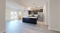 Located at 318 Meadowgreen Dr in Clarksville, Tennessee, this single-story home offers a well-designed layout with consistent, modern finishes throughout. The open-concept kitchen is a standout feature, showcasing dark espresso cabinetry, stainless steel appliances including a refrigerator with ice dispenser, a gas range, and a built-in microwave. A large center island with a dark base and white countertop provides additional prep space and a sink, while stylish pendant lighting adds a contemporary touch. Recessed lighting and vaulted ceilings enhance the sense of openness in the kitchen and living area, which is bathed in natural light from glass-paned French doors. The living spaces feature light gray wood-look flooring that runs throughout the main areas, offering a cohesive and easy-to-maintain surface. Bedrooms are finished with plush neutral carpeting and ceiling fans with light kits, providing comfort and practicality. Windows with blinds allow for natural light and privacy. The bathroom includes a tiled combination tub and shower, a dark navy vanity with white countertop, and oil-rubbed bronze fixtures and accessories, lending a polished, coordinated aesthetic. The overall design is clean, neutral, and move-in ready.