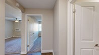Located at 4348 N Chestnut St in Colorado Springs, CO, this single-floor, one-bedroom, one-bathroom unit offers a practical and efficiently designed layout. The kitchen is outfitted with rich dark-wood cabinetry, white countertops, wood-look flooring, and black appliances including a refrigerator, range, and dishwasher, providing ample storage and counter space. The layout transitions smoothly through connecting hallways, lending a sense of flow throughout the unit. The bedroom is a comfortable, well-proportioned room featuring plush carpeting, a ceiling fan with light fixture, a natural light-admitting window with vertical blinds, and a baseboard heating unit. A dedicated closet provides convenient storage directly off the hallway. The bathroom is tastefully finished with a modern wood-toned vanity, white countertop, large mirror, wood-look tile flooring, and a shower/tub combination. Neutral wall tones and textured ceilings carry throughout the unit, creating a cohesive and understated aesthetic. Hardwood-look flooring in the hallways and kitchen contrasts neatly with the carpeted bedroom, adding visual variety. This unit offers a compact yet complete living environment suited for comfortable everyday living.