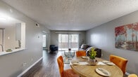 This single-floor, 1-bedroom, 1-bathroom unit offers a thoughtfully designed layout that maximizes comfort and functionality. Dark hardwood-style flooring runs consistently throughout, providing a cohesive and polished look across every room.

The open-concept main area seamlessly connects the living room, dining area, and kitchen. The living room is bright and inviting, anchored by large sliding glass doors fitted with vertical blinds that offer access to an outdoor space and flood the interior with natural light. The adjoining dining area comfortably accommodates a round table and flows naturally into the kitchen, which features grey shaker-style cabinetry, light quartz countertops, stainless steel appliances, and a decorative tile backsplash with blue and white mosaic accents.

The bedroom is a comfortable retreat, offering a well-proportioned layout with a window that lets in natural light and a warm, neutral color palette. The bathroom includes a grey vanity with a white sink basin, a large mirror, and a separate water closet with a shower-tub combination.

A hallway connects the main living spaces to the private areas of the unit. Textured ceilings and neutral grey walls are consistent throughout, creating a calm and modern ambiance well-suited for everyday living.