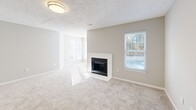 This one-bedroom, one-bathroom residence at 100 Bryton Trce in Columbia, SC offers a well-organized single-level layout with a thoughtful blend of comfort and functionality. The open-concept living room and kitchen area serves as the heart of the home, anchored by a classic white-surround fireplace and framed by multiple windows that flood the space with natural light. Neutral-toned carpet and soft gray walls create a clean, cohesive aesthetic throughout the living areas. The kitchen is a standout feature, showcasing slate-blue cabinetry, light marble-pattern countertops, a center island for additional prep and seating space, wood-look flooring, and black appliances including a refrigerator, range, and under-cabinet range hood. The bedroom is a comfortable, well-lit retreat with two windows, soft carpet, and a textured ceiling. A dedicated closet provides convenient storage. The bathroom is finished with wood-look flooring, a white vanity with ample counter space, a large mirror, and a full tub-shower combination. Textured ceilings are present throughout, adding architectural character. The space is bright, practical, and move-in ready, making it a solid option in the Columbia area.