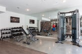 Located at 10820 Abbotts Bridge Rd in Johns Creek, GA, this contemporary fitness center offers a thoughtfully designed, single-floor layout built to accommodate a wide range of workout styles. The space features a clean, modern aesthetic with crisp white walls, recessed lighting, ceiling fans, and a combination of polished concrete and wood-look flooring throughout.

The cardio zone is equipped with multiple Matrix treadmills and Peloton spin bikes, positioned alongside large windows that invite natural light and outdoor views. Wall-mounted flat-screen TVs are distributed throughout the facility for entertainment during workouts.

The strength training area is well-stocked with a full rack of dumbbells, kettlebells, a multi-station cable machine, and additional selectorized equipment. Expansive floor-to-ceiling mirrors amplify the sense of space and allow for proper form checks during exercise.

A dedicated functional training zone features stability balls, medicine balls, resistance bands, and a BOSU trainer, all neatly organized against a striking stacked stone accent wall that adds warmth and texture to the space. Built-in cubbies provide convenient storage for personal items and small equipment.

The facility also includes a water fountain, seating bench, and clearly marked entry and exit points. The overall ambiance is bright, clean, and professional, making this fitness center a comprehensive and inviting space for residents and users alike.