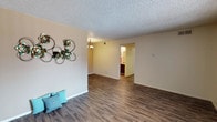 This single-floor unit at 1501 Tramway Blvd NE in Albuquerque, New Mexico offers a well-organized layout designed for comfortable everyday living. The open living area features rich wood-style laminate flooring and neutral-toned walls beneath a textured ceiling, creating a clean and versatile space. Natural light filters in through windows fitted with vertical and horizontal blinds, enhancing the bright, airy feel throughout.

The galley-style kitchen is thoughtfully designed with dark espresso cabinetry lining both walls, dark granite-style countertops, a double-basin sink, and black appliances including a refrigerator and electric range, providing ample storage and workspace for cooking.

The bedrooms are finished with plush wall-to-wall carpeting and feature windows that bring in natural light. At least one bedroom includes a built-in closet with bifold doors and a dedicated rod for hanging storage. The unit includes two full bathrooms, each featuring a shower/tub combination, a vanity with dark cabinetry, and wood-style flooring. Throughout the unit, the consistent use of warm neutral tones and cohesive finishes creates a comfortable and functional living environment.