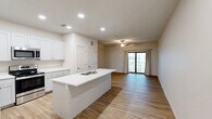 This well-appointed one-bedroom, one-bathroom unit at 1241 Florence St in Nokomis, Florida offers a clean, modern design with thoughtful use of space throughout. The open-concept layout seamlessly connects the kitchen, dining, and living areas, creating a bright and cohesive living environment. Warm-toned wood-look flooring runs consistently throughout the unit, lending a sense of continuity and warmth.

The kitchen is a standout feature, boasting white shaker-style cabinetry, white quartz countertops, and a central island with a built-in sink — ideal for both cooking and casual dining. Stainless steel appliances, including a refrigerator, range, and microwave, complete the modern kitchen aesthetic. Recessed lighting above adds to the clean, polished look.

The living area is bright and airy, anchored by a ceiling fan and a sliding glass door that opens to a private patio, allowing natural light to flow freely into the space. The bedroom is comfortably sized, featuring a ceiling fan and a window with blinds for natural light and privacy. Three closets provide generous storage throughout the unit.

The bathroom features white cabinetry with a quartz vanity top, wood-look flooring, and a tub-shower combination. A dedicated laundry area adds everyday convenience, rounding out this efficiently designed and move-in-ready home.
