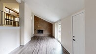 Located at 128 W Woodstock St in Crystal Lake, IL, this two-story, 2-bedroom, 1-bathroom home offers a well-organized layout across two levels. The lower level serves as the entry point, featuring durable wood-look flooring that flows into the living room, where a striking full-height brick accent wall with a wood-burning fireplace commands attention. Vaulted ceilings and a large window flood the space with natural light, while a carpeted staircase with sleek black metal railings leads to the upper level. The kitchen is well-appointed with dark espresso cabinetry, granite countertops, a subway tile backsplash, and stainless steel appliances, including a gas range and refrigerator. An adjacent dining area and hallway connect seamlessly to the staircase. Upstairs, the primary bedroom is generously sized with plush carpet, a double-door closet, and access to a spacious walk-in closet featuring built-in shelving on both sides. The full bathroom includes a tub-shower combo with brushed nickel fixtures. Additional highlights include a balcony, a ground-level patio, in-unit laundry, and abundant closet storage throughout. The home's exterior features a mature tree and landscaped front yard, rounding out this functional Crystal Lake residence.