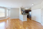 This thoughtfully designed 2-bedroom, 2-bathroom residence offers a comfortable and functional single-floor layout. The open-concept living and kitchen area forms the heart of the home, featuring warm hardwood flooring that extends throughout the main living spaces. The kitchen is equipped with stainless steel appliances, including a full-size refrigerator, range, and microwave, complemented by rich dark wood cabinetry, granite countertops, and a peninsula with pendant lighting — ideal for both meal preparation and casual dining. Natural light flows in through multiple windows, enhancing the bright, neutral-toned interior.

The spacious primary bedroom includes its own dedicated closet and connects to a well-appointed full bathroom featuring a granite-topped double vanity, a soaking tub with tile surround, and a separate glass-enclosed shower. The second bedroom is comfortably sized, finished with plush carpeting, and receives natural light through a large window. A second full bathroom serves this room and guests. Both bedrooms are carpeted, contrasting with the hardwood flooring found throughout the living areas and hallway. A walk-in closet with wire shelving provides generous storage. The hallway connects all rooms efficiently, contributing to the unit's practical and cohesive flow.
