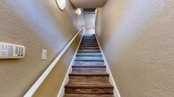 Located at 5009 Park Central Dr in Orlando, FL, this two-bedroom, two-bathroom two-story home offers a thoughtfully laid-out floor plan across two levels. The expansive main floor serves as the heart of the home, encompassing the living room, kitchen, hallways, and a bathroom. The living room is bright and airy, featuring warm wood-look flooring, neutral tan walls, a ceiling fan, and multiple windows that allow natural light to pour in. A staircase with wood-look treads and a white handrail connects the main floor to the upper level, adding a striking vertical element to the interior.

The kitchen is well-appointed with white cabinetry, dark granite-style countertops, white tile flooring, and stainless steel appliances, including a refrigerator, range, and built-in microwave. The bathrooms echo the kitchen's aesthetic with matching dark countertops and white cabinetry, complemented by white tile flooring and a tub-shower combination.

The upper level houses the bedrooms, including a generously sized primary bedroom, each fitted with wood-look flooring, ceiling fans, and ample closet space. The walk-in closets feature wire shelving systems, maximizing storage. Throughout the home, a cohesive warm neutral palette and consistent finishes create a comfortable, unified ambiance.