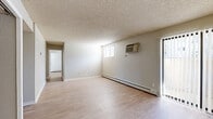 This single-floor, 4-bedroom, 2-bathroom home offers a practical and comfortable layout designed to maximize livable space. Light hardwood-style flooring flows consistently throughout, complemented by neutral-toned walls that create a clean, versatile backdrop.

The living room is generously proportioned, featuring a wall-mounted air conditioning unit, a baseboard heating system, and access to a sliding glass door that allows natural light to pour in. A secondary window adds to the bright, airy atmosphere of the space.

The galley-style kitchen is efficiently designed with warm honey-toned wood cabinetry lining both sides, granite-look countertops, a double sink, and a full-size refrigerator. The layout provides ample storage and counter space, opening toward the rest of the home.

Each of the four bedrooms features the same light flooring, neutral walls, and individual climate control via wall-mounted AC units and baseboard heaters. Several bedrooms include closets, and windows with blinds allow for natural light and privacy. The primary bedroom offers a comfortable, well-proportioned footprint.

Both bathrooms are equipped with a tub-shower combination featuring white tile surrounds, wood vanity cabinetry with granite-look countertops, and light flooring. Two hallways and two closets round out the thoughtfully organized floor plan.