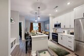 Located at 112 Matheson Ave in Charlotte, NC, this well-appointed 1-bedroom, 1-bathroom residence offers a thoughtfully designed open-concept layout across a single floor. The kitchen serves as the centerpiece of the living space, featuring crisp white shaker cabinetry with matte black hardware, stainless steel appliances including a refrigerator, range, and microwave, a white subway tile backsplash, and a central island with a stainless steel sink and seating — ideal for casual dining or entertaining. Pendant lighting and recessed fixtures illuminate the space, while wood-look flooring runs throughout, adding warmth and continuity. The kitchen flows seamlessly into the living room, which benefits from a large window that draws in natural light. The bedroom is a comfortable retreat, highlighted by a bold accent wall, a window with outdoor views, and dedicated closet space. The bathroom is finished in a clean, modern palette with a white vanity, matte black fixtures, a large framed mirror, and a tiled tub-shower combination. The entry area provides a practical transition point into the home. Clean lines, neutral tones, and contemporary finishes give this Charlotte residence a cohesive and functional character throughout.