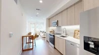 Located at 27942 Forbes Rd in Laguna Niguel, CA, this thoughtfully designed one-bedroom, one-bathroom residence offers a modern aesthetic with clean lines and high-quality finishes throughout. The open-concept layout maximizes the use of space, creating a seamless flow between the kitchen, dining, and living areas.

The galley-style kitchen is outfitted with light wood cabinetry, a textured tile backsplash, white quartz countertops, and stainless steel appliances including a range, microwave, dishwasher, and French door refrigerator. A bar-height counter with seating connects the kitchen to a dedicated dining area, ideal for everyday meals.

The living room is bright and welcoming, featuring recessed lighting, wide-plank hardwood-style flooring, and large windows with a glass door that opens to an outdoor view of lush surroundings, filling the space with natural light.

The bedroom is a comfortable retreat with a ceiling fan, a sizeable window framing outdoor views, and direct access to a well-organized closet with built-in shelving and hanging rails. A built-in desk nook near the entryway provides a practical workspace.

Marble-look tile flooring accents the bathroom and entry areas, adding an elegant contrast to the warm wood floors found throughout the rest of the home.