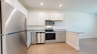 Located in Spring Hill, TN, this well-appointed 1-bedroom, 1-bathroom unit offers a thoughtfully designed single-level layout that maximizes every square foot. Light hardwood-style flooring runs seamlessly throughout, creating a cohesive and airy feel across all rooms.

The open kitchen is a standout feature, showcasing a full suite of stainless steel appliances — including a refrigerator, range, over-the-range microwave, and dishwasher — paired with granite countertops and a two-tone cabinet design of crisp white upper cabinets and gray lower cabinets. A peninsula counter adds extra prep space and visually connects the kitchen to the main living area, which is bright and open with recessed lighting above.

The bedroom is a comfortable and private retreat, featuring a ceiling fan, a window with natural views of surrounding greenery, and access to a well-organized closet with mirrored doors and built-in shelving. The clean white walls and consistent flooring lend a calm, neutral atmosphere.

The bathroom is finished with the same attention to detail, offering a tiled tub-shower combination, granite vanity countertop, and brushed nickel fixtures — all set against a clean, white palette. The overall design of this unit is modern, clean, and move-in ready.
