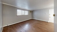 Located at 600 Stevens Dr in Pittsburgh, PA, this one-bedroom, one-bathroom residence offers a practical and comfortable single-floor layout. The living room is a generously sized space finished with rich hardwood flooring, neutral gray walls, and a textured ceiling. Natural light filters in through horizontal-blind-covered windows, while a wall-mounted air conditioning unit and baseboard heating provide year-round climate control. The galley-style kitchen is efficiently designed with ample white cabinetry reaching to the ceiling, white laminate countertops, a double-basin sink, and white appliances including a refrigerator and electric range — all set atop light wood-tone flooring. The spacious primary bedroom is carpeted in soft gray and features a ceiling fan, two full-width closets offering generous storage, and a window that brings in natural light. Baseboard heating runs along the perimeter of the bedroom as well. The bathroom includes a full tub-shower combination with panel surround. Throughout the unit, a consistent neutral gray color palette and clean white trim create a cohesive, move-in-ready atmosphere suited for comfortable everyday living.