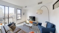 Located at 728 Market St in the heart of Chattanooga, TN, this modern single-floor unit offers a thoughtfully designed open layout with clean lines and a contemporary aesthetic throughout. The living area is bright and welcoming, featuring large windows that frame city views and flood the space with natural light. A distinctive horizontal clerestory window adds an architectural detail that enhances the sense of openness. The galley-style kitchen is efficiently arranged and well-appointed, featuring granite-style countertops, dark cabinetry, stainless steel appliances including a refrigerator, dishwasher, and electric range, as well as an open display shelf above the counters. Wood-look flooring runs through the kitchen and entry corridor, lending warmth to the space. The bedroom is a calm, neutral retreat highlighted by a matching clerestory window, soft carpeting, and a spacious reach-in closet with built-in shelving for ample storage. The bathroom is finished with large-format tile flooring, dark cabinetry with a granite-topped vanity, and a full tub-shower combination. The overall design balances modern minimalism with functional comfort, making it a well-suited urban residence in downtown Chattanooga.
