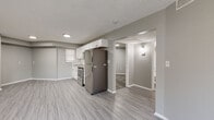 Located at 8014 Tommy Ct in Tampa, FL, this thoughtfully renovated single-story home showcases a clean, modern aesthetic carried consistently throughout every room. Light gray luxury vinyl plank flooring runs seamlessly across the entire interior, complementing the neutral gray walls and crisp white trim to create a bright, cohesive atmosphere.

The open-concept living and kitchen area serves as the heart of the home. The kitchen is well-appointed with white shaker-style cabinetry, granite-look countertops, a classic white subway tile backsplash, and a full suite of stainless steel appliances, including a refrigerator, range, and over-the-range microwave. Recessed lighting illuminates the combined living and dining space, which offers generous room to arrange furnishings comfortably.

The bedrooms are spacious and offer ample closet space with standard panel doors. Each room is finished with the same consistent flooring and neutral tones, providing a versatile backdrop. A dedicated laundry area with a stacked washer and dryer unit adds notable convenience. The bathroom features a full tub-shower combo with clean white surround, coordinating fixtures, and matching vinyl plank flooring. Textured ceilings and recessed lighting complete the refreshed interior of this move-in-ready Tampa home.
