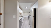 Located at 16W571 Mockingbird Ln in Willowbrook, IL, this single-floor, one-bedroom, one-bathroom unit offers a thoughtfully designed layout that maximizes its well-proportioned footprint. The galley-style kitchen is a standout feature, showcasing crisp white shaker cabinetry, granite stone countertops, a stainless steel refrigerator, dishwasher, and range, all complemented by light wood-look luxury vinyl flooring that extends throughout the main living areas. Recessed and flush-mount ceiling lighting keeps the kitchen bright and functional. The kitchen flows seamlessly into the open living area, which benefits from a sliding glass door that brings in natural light and provides outdoor access. The spacious bedroom offers generous square footage with plush neutral carpeting and soft, warm-toned walls, creating a comfortable and restful retreat with ample room for furnishings. The bathroom is cleanly finished with a gray vanity topped with a white countertop, a framed mirror, chrome fixtures, and coordinating wood-look flooring, giving it a modern and polished appearance. A dedicated closet and hallway round out the layout, providing practical storage. The unit's neutral color palette and updated finishes throughout lend a clean, move-in-ready aesthetic.