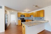 This thoughtfully designed single-floor residence in Jackson, Michigan, offers a comfortable and functional layout across a well-utilized footprint. The open-concept living and dining area features rich hardwood flooring, a cozy fireplace, and a seamless connection to the kitchen, creating an inviting space for both relaxing and entertaining. The kitchen is a standout highlight, showcasing warm honey-toned cabinetry, striking granite countertops, a speckled tile backsplash, and black appliances, including a range, microwave, and dishwasher. A breakfast bar with bar seating adds casual dining convenience. The bedroom is a calm retreat with plush carpeting, natural light from a window with outdoor views, and access to a generously sized walk-in closet outfitted with wire shelving for ample storage. A dedicated office provides a bright, functional workspace with a large window overlooking greenery and a built-in closet. The bathroom continues the granite and warm wood cabinetry theme, complete with tile flooring and a shower. Throughout the space, neutral tones and clean lines create a cohesive, modern aesthetic that is both practical and welcoming.