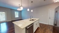 Located at 3501 Patterson Ave in Richmond, Virginia, this single-floor unit offers a well-designed, open-concept layout finished with contemporary fixtures and quality materials throughout. Rich, dark hardwood-style flooring runs continuously across the living and bedroom areas, creating a cohesive and polished aesthetic that anchors the entire space.

The kitchen serves as a focal point of the unit, centered around a sizeable island topped with light granite countertops and fitted with a stainless steel undermount sink. Pendant lighting hangs above the island, complementing the surrounding white shaker cabinetry and a full suite of stainless steel appliances, including a refrigerator with ice and water dispenser, range, microwave, and dishwasher. The kitchen opens directly into the living and dining areas, which are illuminated by natural light from double-hung windows and accented by modern overhead fixtures.

The bedrooms are generously proportioned, each featuring ceiling fans, ample natural light, and closet storage with classic paneled doors. Neutral wall tones throughout lend a calm, versatile backdrop.

The bathrooms are finished with clean, tile work — one features a tub-shower combination with white subway tile and a bold dark accent border, while another offers an elongated vanity with granite countertops, white cabinetry, and large-format tile flooring, bringing a spa-like quality to the space.