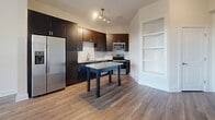 Located in Charlotte's Brooklyn Village neighborhood, this one-bedroom, one-bathroom residence offers a thoughtfully designed single-floor layout with modern finishes throughout. Wood-style luxury flooring flows seamlessly across every room, creating a cohesive and contemporary aesthetic.

The open-concept kitchen and living area serves as the heart of the home. The kitchen is outfitted with rich dark espresso cabinetry, stainless steel appliances including a range, microwave, and refrigerator, a tile backsplash, and granite countertops. A central island provides additional prep and dining space. The living area is bright and airy, featuring a ceiling fan, neutral walls, and a glass door that opens to a private balcony, allowing natural light and outdoor views to enhance the space.

The bedroom is comfortably sized, offering natural light through large windows with outdoor views, wood-style flooring, and a ceiling fan. A dedicated closet provides practical storage.

The bathroom features a dark-toned vanity with granite countertops, a framed mirror, and a full tub-shower combination with tile surround and brushed nickel fixtures. A hallway connects the rooms efficiently, completing the functional layout. Built-in shelving in the living area adds a distinctive architectural detail to this clean, modern residence.