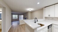 Located at 4901 Tall Timber Dr in Raleigh, NC, this 2-bedroom, 2-bathroom residence offers a well-designed single-floor layout with a clean, modern aesthetic throughout. Light wood-tone flooring runs continuously across the living areas, complementing the neutral warm-gray walls and white trim.

The open-concept kitchen features white shaker cabinetry with black hardware, white quartz countertops, a tile backsplash, and stainless steel appliances including a refrigerator, range, and over-the-range microwave. A peninsula with an undermount sink and matte black faucet provides a natural transition into the living area.

The living room is bright and welcoming, showcasing a tile-surround fireplace with a white mantel, a large window, and sliding glass doors that open to a private balcony with wooded views beyond.

The spacious primary bedroom includes a dedicated closet and an en-suite bathroom finished with white quartz countertops, an undermount sink, black fixtures, and a framed mirror. The second bedroom is well-proportioned with a natural light source. A second full bathroom features a clean white tub-shower combination. Two closets provide ample storage. Textured ceilings are consistent throughout the home.