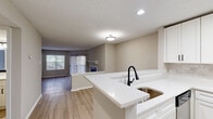 Located at 4901 Tall Timber Dr in Raleigh, NC, this 2-bedroom, 2-bathroom residence offers a well-designed single-floor layout with a clean, modern aesthetic throughout. Light wood-tone flooring runs continuously across the living areas, complementing the neutral warm-gray walls and white trim.

The open-concept kitchen features white shaker cabinetry with black hardware, white quartz countertops, a tile backsplash, and stainless steel appliances including a refrigerator, range, and over-the-range microwave. A peninsula with an undermount sink and matte black faucet provides a natural transition into the living area.

The living room is bright and welcoming, showcasing a tile-surround fireplace with a white mantel, a large window, and sliding glass doors that open to a private balcony with wooded views beyond.

The spacious primary bedroom includes a dedicated closet and an en-suite bathroom finished with white quartz countertops, an undermount sink, black fixtures, and a framed mirror. The second bedroom is well-proportioned with a natural light source. A second full bathroom features a clean white tub-shower combination. Two closets provide ample storage. Textured ceilings are consistent throughout the home.