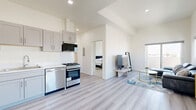 Located at 983 Dewey Ave in Los Angeles, this modern 1-bedroom, 1-bathroom unit offers a thoughtfully designed open-concept layout with high ceilings and light wood-style flooring throughout. The combined kitchen and living area creates a seamless flow, anchored by a well-appointed kitchen featuring gray shaker-style cabinetry, white countertops, subway tile backsplash, and a full suite of stainless steel appliances including a gas range, dishwasher, and refrigerator. The bright living area benefits from large windows and a sliding glass door opening to a private balcony, both framing sweeping views of the Los Angeles cityscape. The spacious bedroom is filled with natural light from a generously sized window overlooking the city, and includes a closet with mirrored sliding doors. The bathroom stands out with striking marble-patterned tile walls in the walk-in shower, a bold navy vanity, and light wood-style flooring that ties the space together. Clean white walls and recessed lighting throughout contribute to a fresh, contemporary ambiance that makes this Los Angeles residence feel bright, airy, and move-in ready.