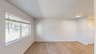 This studio in Phoenix, Arizona offers a thoughtfully laid-out single-floor living space designed for efficiency and comfort. The main living area is bright and open, featuring light wood-style flooring and clean white walls that create a fresh, airy atmosphere. A window with blinds allows natural light to fill the room, enhancing the sense of space. The flooring continues cohesively throughout, tying the areas of the studio together visually.

Toward the rear of the living area, an open pass-through leads into a compact kitchen outfitted with white cabinetry, a white range, a sink, and a tile backsplash. Ceiling-mounted light fixtures illuminate both the living and kitchen zones. HVAC vents are integrated into the ceiling, providing climate control well-suited to the Arizona heat.

The bathroom is accessible via a door off the main space and features the same wood-style flooring. It includes a soaking tub with marble-style tile surround, a toilet, and a small window that provides natural ventilation and light. The white walls and clean finishes maintain a consistent, neutral aesthetic throughout.

Overall, this studio presents a practical and well-maintained living space in the desirable 85018 zip code of Phoenix, offering a clean, move-in-ready environment with a cohesive design palette.