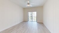 Located at 26710 SW 140th Ave, Unit 304 in Homestead, FL, this two-bedroom, two-bathroom residence offers a well-organized layout across a single primary floor. The open-concept living area is bright and airy, anchored by light wood-style tile flooring that extends throughout the unit. The kitchen is equipped with white cabinetry, stainless steel appliances including a full-size refrigerator, a built-in dishwasher, and a peninsula countertop with a neutral gray surface — ideal for casual dining or meal prep. A pendant light fixture and a skylight above add warmth and natural illumination to the space. The living room flows seamlessly toward sliding glass doors that open onto a private balcony, where palm-lined community views and Florida's open skies can be enjoyed. A ceiling fan overhead keeps the living area comfortable year-round. The primary bedroom features a mirrored sliding closet, elevated ceilings, and its own access to the hallway. Both bathrooms are cleanly finished, with one featuring a full tub-shower combination with white tile surround. Additional highlights include a dedicated laundry area, a utility room, and two closets for ample storage throughout the unit.