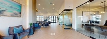 This contemporary 3,270 square foot facility in Avondale, Arizona, showcases a versatile and thoughtfully designed interior. The space is characterized by its open layout and abundant natural light, enhanced by high ceilings and large windows. The main area features glass-enclosed meeting rooms and workspaces, providing both transparency and privacy. A state-of-the-art fitness center is equipped with a variety of exercise machines, catering to diverse workout preferences. The facility also includes multiple lounge areas furnished with comfortable seating, creating inviting spaces for relaxation or informal gatherings. A standout feature is the modern kitchenette and bar area, complete with pendant lighting and bar seating. For added convenience, there's an on-site store stocked with refreshments and snacks. The interior design maintains a cohesive aesthetic throughout, with a neutral color palette accented by pops of blue, and a mix of materials including wood, glass, and textiles. This multifunctional space effectively balances practicality with style, suitable for various purposes from work to leisure.