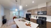 Located at 2635 Nez Perce Dr in Lewiston, Idaho, this thoughtfully designed one-bedroom, one-bathroom unit offers a modern and efficient layout across a single floor. The open-concept living, dining, and kitchen area forms the heart of the space, creating a seamless flow ideal for everyday living and entertaining. The kitchen is a standout feature, showcasing rich walnut-toned cabinetry, light quartz countertops, a large peninsula island with an undermount sink, and stylish pendant lighting overhead. Black appliances including a range, microwave, and refrigerator complete the functional kitchen setup. Light wood-style flooring runs throughout the main living areas, enhancing the bright and airy feel of the space. The living room is well-proportioned with a large window that invites natural light and outdoor views of the Lewiston cityscape. The bedroom offers plush carpeting, a ceiling fan, a window with exterior views, and two closets for ample storage. The bathroom features a clean, full-size soaking tub and shower combination with white surround walls and wood-style flooring. An in-unit laundry area adds everyday convenience, rounding out this well-appointed and move-in-ready home.