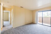 This single-floor residence offers a practical and comfortable layout with a warm, neutral color palette throughout. The living area is spacious and carpeted in plush grey, with soft yellow walls that lend a welcoming ambiance. A sliding glass door opens directly to a private outdoor balcony, allowing natural light to flow into the space and providing a pleasant outdoor view. The front entry transitions from light hardwood-style flooring into the carpeted living area, creating a clear delineation between zones.

The kitchen is efficiently designed with white cabinetry, dark granite-style countertops, and an electric range with overhead ventilation. The layout maximizes counter and storage space, making it a functional area for everyday cooking.

The bedrooms are generously proportioned, each featuring plush carpet, neutral walls, and sliding mirrored or standard closet doors with built-in rod storage. Natural light enters through windows with outdoor views. One bedroom area features hardwood-style flooring and a ceiling fan with integrated lighting.

The bathroom includes hardwood-style flooring, a shower and tub combination with a curtain, and brushed nickel hardware accents. The overall layout of this residence is well-organized, offering comfortable, move-in-ready living spaces throughout.