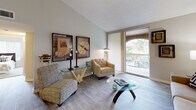 Located at 1853 Coral Ridge Dr in Coral Springs, Florida, this single-floor residence offers a thoughtfully designed open layout that connects its key living spaces seamlessly. The living room features light wood-style flooring, vaulted ceilings, and large sliding glass doors that open to a private balcony, allowing abundant natural light and outdoor views of lush Florida greenery. A separate seating area provides additional versatility for the space.

The dining area is situated adjacent to the living room and accommodates a round table, complemented by tasteful wall art that adds a sophisticated touch to the room.

The kitchen is well-equipped with dark espresso cabinetry, light countertops, stainless steel appliances including an electric range and over-the-range microwave, and a dishwasher — offering ample storage and functional workspace.

The bedrooms are carpeted for comfort, each featuring ceiling fans, vertical blinds, and generous windows that invite natural light. The primary bedroom includes an arched window detail and mirrored closet doors, enhancing the sense of space.

Both bathrooms are finished with light ceramic tile flooring, dark wood vanity cabinetry, white countertops, and tub-shower combinations with tile surrounds, providing a clean and cohesive aesthetic throughout.