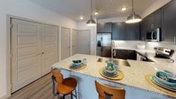 Located at 2005 W Campbell Rd in Garland, Texas, this single-story residence showcases a thoughtfully designed layout with modern finishes throughout. The open-concept kitchen serves as a central highlight, featuring dark charcoal shaker-style cabinetry, granite countertops, a tile backsplash, and a full suite of stainless steel appliances including a refrigerator with ice maker, range, microwave, and dishwasher. A kitchen island with pendant lighting overhead provides bar-style seating, making it ideal for casual dining and entertaining.

The living area offers wood-style flooring, a ceiling fan, and large windows with shuttered blinds that allow natural light to fill the space. The bedrooms are generously sized, each featuring ceiling fans and ample closet storage. One bedroom includes plush carpeting and a large window with views of the surrounding community. The primary bedroom connects directly to a private en-suite bathroom, which features a granite-topped vanity with dark cabinetry, wood-style flooring, a glass-enclosed shower, and convenient access to closet space. Additional closets are visible near the entryway, providing practical storage throughout. The overall aesthetic is clean, contemporary, and cohesive.