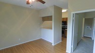 This single-floor residence offers a practical and well-connected layout designed for comfortable everyday living. The main living area features light hardwood flooring that extends throughout, creating a warm and cohesive feel underfoot. A ceiling fan is installed overhead, providing efficient air circulation and adding a functional accent to the space.

A defining architectural feature is the built-in pass-through counter that connects the living area to the kitchen, topped with upper cabinetry in a warm wood finish. This design element enhances the open feel of the space while maintaining a natural separation between the living and cooking zones.

The kitchen is equipped with stainless steel appliances, including a range and microwave, complemented by matching wood-toned cabinetry that provides ample storage. The neutral, light-toned walls throughout the space create a clean, versatile backdrop that adapts well to a variety of interior styles.

Overall, the space presents a straightforward, functional layout with consistent finishes, making it well-suited for those seeking a move-in-ready environment with a cohesive and uncluttered design aesthetic.