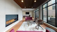 Located at 199 Rantoul Street in Beverly, Massachusetts, this thoughtfully designed amenity floor delivers a diverse range of social, recreational, and wellness spaces under one roof. The centerpiece of the floor is a generously sized lounge area distinguished by a striking slatted wood ceiling, a sleek linear gas fireplace set against a dramatic accent wall, and floor-to-ceiling windows that bathe the space in natural light while offering views of the surrounding outdoor terrace. Plush seating, including tufted velvet sofas and sculptural lounge chairs, lends a warm yet contemporary feel, while a pool table positioned nearby adds a recreational focal point. An adjoining co-working and social area features a wall-mounted television, mid-century modern seating, a high-top table with dark stone surface, and bar-height seating—ideal for casual meetings or relaxed gatherings. The fitness center is comprehensively outfitted with cardio machines, cable systems, free weights, a dedicated stretch and studio room with floor-to-ceiling mirrors, and a mounted television, all finished with easy-care hardwood-style flooring. Throughout the entire floor, light wood flooring, recessed lighting, and clean modern finishes create a cohesive, polished aesthetic that balances functionality with comfort.