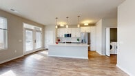 Located at 4301 Yates Dr in Mount Pleasant, WI, this single-floor, one-bedroom, one-bathroom home offers a thoughtfully designed layout with modern finishes throughout. The open-concept kitchen and living area serves as the heart of the home, featuring light hardwood-style flooring, a large central island with a white quartz countertop and undermount sink, white shaker-style upper cabinets, and contrasting gray lower cabinetry. Stainless steel appliances — including a refrigerator, range, and over-the-range microwave — complete the kitchen. Pendant lighting over the island adds a stylish touch. The living area is bright and welcoming, with large windows and a glass-paneled front door that flood the space with natural light and offer views of the surrounding neighborhood. The spacious bedroom is carpeted for comfort, features a generous closet with double doors, and is lit by a large window. The full bathroom is equipped with a tub-shower combo, grab bars, and wood-look tile flooring. Additional spaces include a dedicated laundry room and utility room, providing practical storage and functionality. Neutral tones and clean architectural lines give the home a fresh, modern feel throughout.