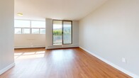 Located at 2000 Main St W in Hamilton, Ontario, this one-bedroom, one-bathroom unit offers a thoughtfully laid-out single-floor living space. Warm hardwood flooring runs throughout the living areas and bedroom, complemented by neutral grey walls and clean white trim that create a bright, cohesive ambiance. The living room is generously proportioned, featuring large windows and a sliding glass door that opens to a balcony, filling the space with abundant natural light and offering pleasant views of the surrounding greenery and hillside landscape. Baseboard heating lines the perimeter of the main living areas, ensuring year-round comfort. The galley-style kitchen is efficiently designed with white cabinetry, a stainless appliance package including a range, and light tile flooring that contrasts neatly with the hardwood in the adjoining spaces. The bedroom is a comfortable size, appointed with the same warm hardwood floors, wide windows that frame scenic outdoor views, and a full-width sliding door closet providing ample storage. The bathroom features classic white subway tile surrounding the bathtub, a tiled floor, a white vanity with a warm stone-toned countertop, and brushed nickel hardware, lending a clean and timeless finish to the space.
