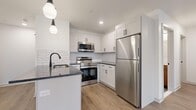 Located at 458 Parker Ave in Philadelphia's Roxborough neighborhood, this thoughtfully designed one-bedroom, one-bathroom unit offers a clean, modern aesthetic across a well-utilized single floor. Light-toned hardwood-style flooring flows throughout, complementing the bright white walls and recessed lighting that keep the space feeling open and airy.

The combined kitchen and living area serves as the heart of the unit. The kitchen is outfitted with white shaker cabinetry, a white subway tile backsplash, dark granite countertops, and a full suite of stainless steel appliances including a refrigerator, range, and over-the-range microwave. A peninsula with pendant lighting provides additional prep space and casual seating potential. A stacked washer and dryer is conveniently tucked behind a dedicated closet door nearby.

The bedroom is a comfortable, well-proportioned room featuring a window with natural light, a wall-mounted thermostat, and direct access to a dedicated walk-in closet with built-in shelving.

The bathroom features large-format grey floor tile, a soaking tub with full hexagonal tile surround, matte black fixtures, and a warm wood-toned vanity with a white countertop — a refined blend of modern and natural materials throughout.