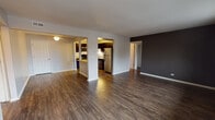 Located at 2386 S Goebbert Rd in Arlington Heights, Illinois, this single-floor residence offers a thoughtfully designed layout with a cohesive modern aesthetic. The open-concept living and dining area is anchored by rich, dark hardwood-style flooring and neutral walls accented by a bold charcoal feature wall, creating a warm yet contemporary atmosphere. A ceiling fan adds both function and character to the space.

The kitchen is well-equipped and visually striking, featuring dark espresso cabinetry, granite-style countertops, and a full suite of stainless steel appliances, including a refrigerator, gas range, microwave, and dishwasher. A breakfast bar connects the kitchen to the main living area, enhancing the open feel and making it ideal for everyday dining or entertaining.

The bedrooms offer comfortable retreats — one features dual windows that invite natural light and views of the surrounding neighborhood, paired with dark hardwood-style floors, while another is finished with plush grey carpeting for added comfort. Both provide a calm, neutral palette.

The unit includes two bathrooms: a full bath with a tub/shower combination, granite-topped vanity, dark cabinetry, and tile flooring, as well as a half bath with a matching vanity and tile floor. Together, these spaces deliver a clean, functional design throughout.