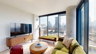 Located on the 10th floor at 220 North Ada Street in Chicago's vibrant West Loop neighborhood, this two-bedroom, two-bathroom residence offers a well-designed single-level layout with contemporary finishes throughout. The open-concept kitchen and living area is a standout feature, anchored by a sleek kitchen with light wood cabinetry, a white subway tile backsplash, dark stone countertops, a central island with pendant lighting, and a stainless steel gas range. Floor-to-ceiling windows flood the space with natural light and frame sweeping views of the Chicago skyline, visible from both the living room and the primary bedroom. The living area offers an airy, comfortable atmosphere enhanced by light hardwood flooring that runs throughout the home. The spacious primary bedroom features large-format windows showcasing iconic city views, generous wardrobe storage, and an exposed concrete accent wall that adds an industrial touch. The second bedroom is equally well-appointed with ample closet space. Both bathrooms reflect a clean, modern aesthetic — the primary bath includes a wide double-sink vanity with a light countertop, an arched mirror, and wood flooring, while the second bath features a single vanity with black fixtures and a similarly styled arch mirror.