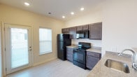 This single-story apartment at Windhurst Park Apartments offers a clean, functional layout designed for comfortable everyday living. The kitchen is a standout feature, showcasing rich dark-brown cabinetry that provides ample storage space, complemented by granite-style countertops that add a touch of sophistication. Black appliances, including a full-size refrigerator, electric range, and over-the-range microwave, are seamlessly integrated into the design for a cohesive, modern aesthetic. Light-toned luxury vinyl plank flooring runs throughout, offering both durability and a bright, airy feel underfoot. Recessed lighting in the ceiling provides even, practical illumination across the kitchen area. A window dressed with horizontal blinds allows natural light to filter in while maintaining privacy. The neutral wall tones and light-colored flooring create a welcoming atmosphere that is easy to personalize. The overall design balances practicality with style, making this apartment a well-rounded living space suited for a variety of lifestyles.