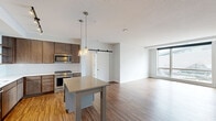 Located on the 14th floor at 801 S Washington Ave in downtown Minneapolis, this well-appointed 3-bedroom, 3-bathroom residence offers a thoughtfully designed open-concept layout. The kitchen is a standout feature, showcasing rich walnut-toned cabinetry, stainless steel appliances including a gas range and French door refrigerator, a classic white subway tile backsplash, open shelving, and a central island with pendant lighting — all set atop warm hardwood flooring. The adjoining living area benefits from large floor-to-ceiling windows that flood the space with natural light and frame striking views of U.S. Bank Stadium and the surrounding cityscape. The three bedrooms offer a mix of hardwood and plush carpet flooring, with exposed concrete structural columns adding an industrial character unique to the building's architecture. A sliding barn door accents one of the bedrooms. The three bathrooms are finished with subway tile, large-format floor tile, and dark wood vanities with white countertops — one featuring a walk-in glass-enclosed shower, another a soaking tub. The hallway connects the spaces efficiently, contributing to a clean, functional flow throughout this urban residence.