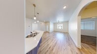 This well-designed two-bedroom, two-bathroom unit at 185 S Colvin St in Colorado City, Arizona, offers a thoughtfully laid-out single-level floor plan that maximizes every square foot of its compact yet functional footprint. The open-concept kitchen and living area forms the heart of the unit, where light wood-style flooring, a textured ceiling, and a ceiling fan create a bright, welcoming atmosphere. A window at the far end of the living room allows natural light to filter through, enhancing the airy feel of the space.

The kitchen is a standout feature, showcasing contemporary wood-grain cabinetry extending to the ceiling, stainless steel appliances including a range, microwave, dishwasher, and French door refrigerator, and crisp white countertops. A peninsula with pendant lighting and an integrated sink connects the kitchen to the living area, making it ideal for both cooking and entertaining. A decorative arched passageway adds architectural character, leading to a walk-in pantry or closet nearby.

Both bedrooms are carpeted and receive natural light through windows with exterior views. The bathrooms are clean and functional, each featuring a tiled tub-and-shower combination with brushed gold fixtures and wood-look flooring, contributing a modern, cohesive aesthetic throughout the unit.