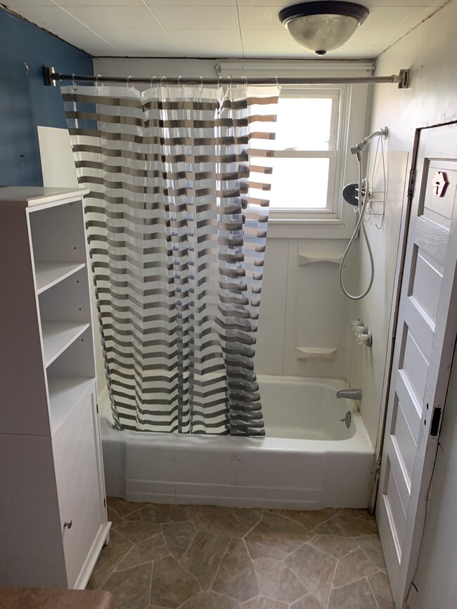In bathroom view of shower/tub. The door on the right leads to the water heater room. - 410 Church St.