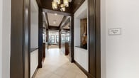 Located in Lake Mary, Florida, this upscale fitness center offers a generously sized, single-floor layout designed to accommodate a full range of workout activities. The space is defined by its sophisticated architectural character, featuring dark espresso-toned columns, crown molding, tray ceilings, and a consistent contrast of rich dark trim against crisp white walls throughout.

The facility is organized into distinct functional zones. A dedicated strength training area is outfitted with a comprehensive selection of cable machines and resistance equipment, complemented by large floor-to-ceiling mirrors that enhance the sense of space. A cardio zone features treadmills and elliptical machines positioned near windows that allow natural light to filter in. A functional training alcove houses a TKO dual rack system stocked with medicine balls, kettlebells, a battle rope, and a heavy bag, catering to high-intensity and functional workouts.

An open studio area with rich hardwood flooring and a mirrored wall provides ample room for stretching, yoga, or group exercise. Ceiling fans are positioned throughout to maintain airflow and comfort. The entrance corridor features elegant pendant lighting and a built-in decorative niche, setting a refined tone upon arrival. The overall ambiance balances a polished, club-quality aesthetic with practical, purpose-built fitness infrastructure.